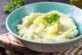 Mashed cauliflower with oil in blue bowl on wooden table.