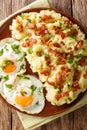 Mashed potato with bacon served with fried eggs close-up on a plate. Vertical top view