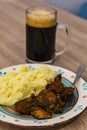 Mashed potato with pork meat made with spices and a mug of black beer Royalty Free Stock Photo