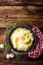 Mashed potatoes, boiled puree in cast iron pot on dark wooden rustic background, top view, copy space