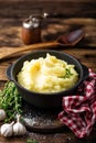 Mashed potatoes, boiled puree in cast iron pot on dark wooden rustic background, top view, copy space