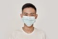 Mask on. Portrait of young asian man wearing medical mask, smiling at camera over white background. Health care