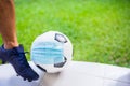 Mask wearing to soccer ball with foot and sport shoe of soccer player Royalty Free Stock Photo