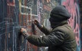 Masked artist in the process of creating vibrant graffiti on an urban wall.