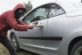 Masked bandit opens the Central lock of an expensive modern car with the help of a mobile phone. Connect to MirrorLink. Royalty Free Stock Photo