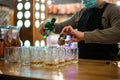 The masked bartender pours a strong alcoholic drink. COVID-19.