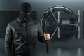 Masked burglar with crowbar in the background. Bank vault doors, large safe, bank robbery. The concept of deposit protection,