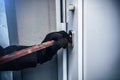 Masked burglar with crowbar breaking and entering into a victim  home Royalty Free Stock Photo