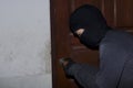 Masked burglar with lock picking tools breaking and entering into house. Crime concept Royalty Free Stock Photo