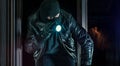 Masked burglar with torch and crowbar breaking and entering into a house
