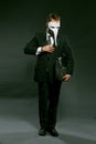 Masked businessman puts large wad of money in his breast pocket holding briefcase under his arm. Man in fancy white