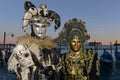 Masked couple in black and gold carnival costumes