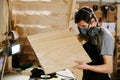 Masked craftsman checking a square wooden plank. In a big workshop. Royalty Free Stock Photo