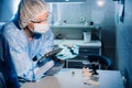 A masked and gloved dental technician works on a prosthetic tooth in his lab