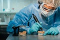 A masked and gloved dental technician works on a prosthetic tooth in his lab