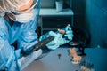 A masked and gloved dental technician works on a prosthetic tooth in his lab