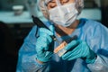 A masked and gloved dental technician works on a prosthetic tooth in his lab