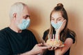 Masked Grandfather gives the joyful granddaughter birthday cake and supports in difficult times during isolation. Misses friends d