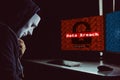 Masked hacker under hood using computer to commit data breach cr Royalty Free Stock Photo