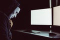 Masked hacker under hood using computer to hack into system and trying to commit computer crime. Royalty Free Stock Photo