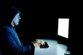 Masked hacker under hood using computer to hack into system and trying to commit computer crime. Royalty Free Stock Photo