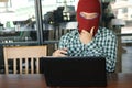 Masked hacker wearing a balaclava looking a laptop and stealing important information data. Network security and privacy crime con