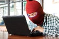 Masked hacker wearing a balaclava stealing importance data from laptop. Internet crime concept. Royalty Free Stock Photo