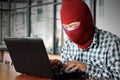 Masked hacker wearing a balaclava stealing information data with laptop. Internet crime concept. Royalty Free Stock Photo