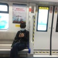 A masked lady is playing her cellphone on Shenzhen metro