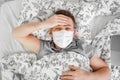 Masked male lies at home bed and sick. stay home