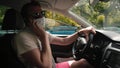 Masked man uses phone while driving a car. He replies to the message.