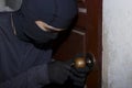 Masked thief with balaclava entering and breaking into a house at night time. Crime concept. Royalty Free Stock Photo