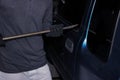 Masked thief with balaclava using crowbar to breaking into a car. Crime concept Royalty Free Stock Photo