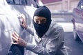 Masked thief in black balaclava trying to break into car. Criminal crime concept Royalty Free Stock Photo