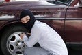 Masked thief in black balaclava trying to break into car. Criminal crime concept Royalty Free Stock Photo