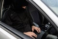 Masked thief hacker in a balaclava disarming car security systems Royalty Free Stock Photo