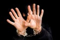 Masked thief in handcuffs isolated on black background