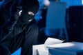 Masked thief holding and reading confidential documents Royalty Free Stock Photo