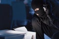 Masked thief holding and reading confidential documents Royalty Free Stock Photo