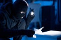 Masked thief holding and reading confidential documents Royalty Free Stock Photo