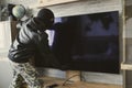 Masked thief removes an expensive TV from the wall. The concept of apartment theft