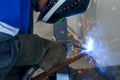 Masked welder works in workshop and sparks fly. Close-up portrait. Industrial background. Authentic workflow.