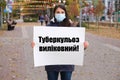 A masked woman holds a poster with text in Ukrainian, translated from Ukrainian - Tuberculosis is curable