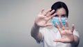 Masked woman makes stopping hand gesture. Stop coronavirus or covid 19 outbreak concept