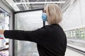 Masked woman in the supermarket. A young blonde takes food in glass showcases for freezing. Coronavirus pandemic period