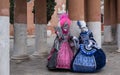 Masked women in brightly colored pink and blue costumes at Venice Carnival Royalty Free Stock Photo