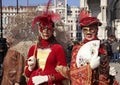 Masked women in red costume on San Marco Square, Venice