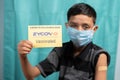 Maski, India - October 26, 2021 : Young kid with medical face mask showing ZYCOV-D Covid-19 or coronavirus Vaccinated report card