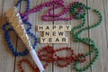 Masks and beads for Happy New Year on wood background