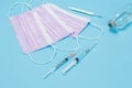 Masks, syringes and a glass mercury thermometer on a blue background
